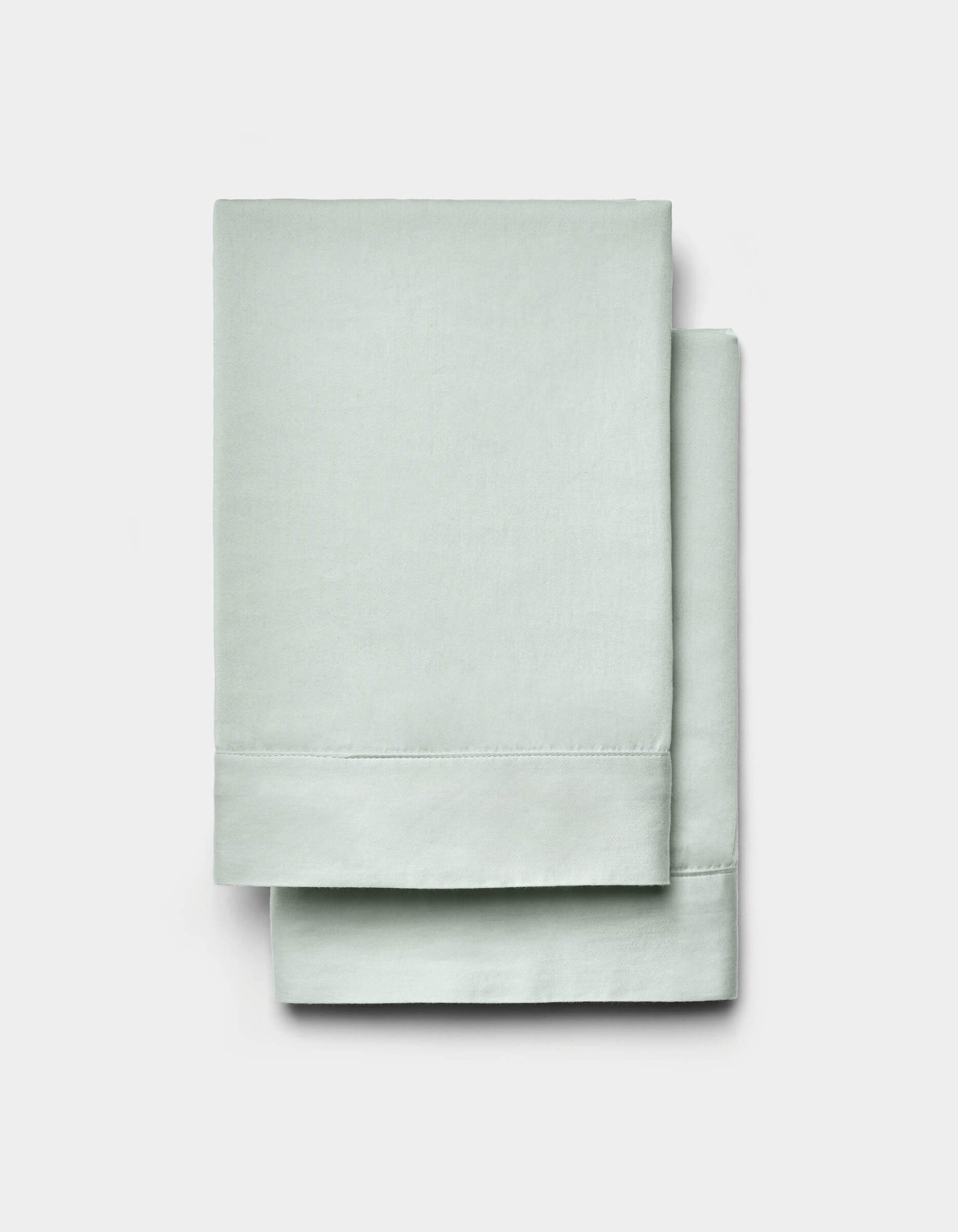 A pair of Cozy Earth Soft-Wash Cotton Shams in light green is neatly folded and displayed against a plain white background.