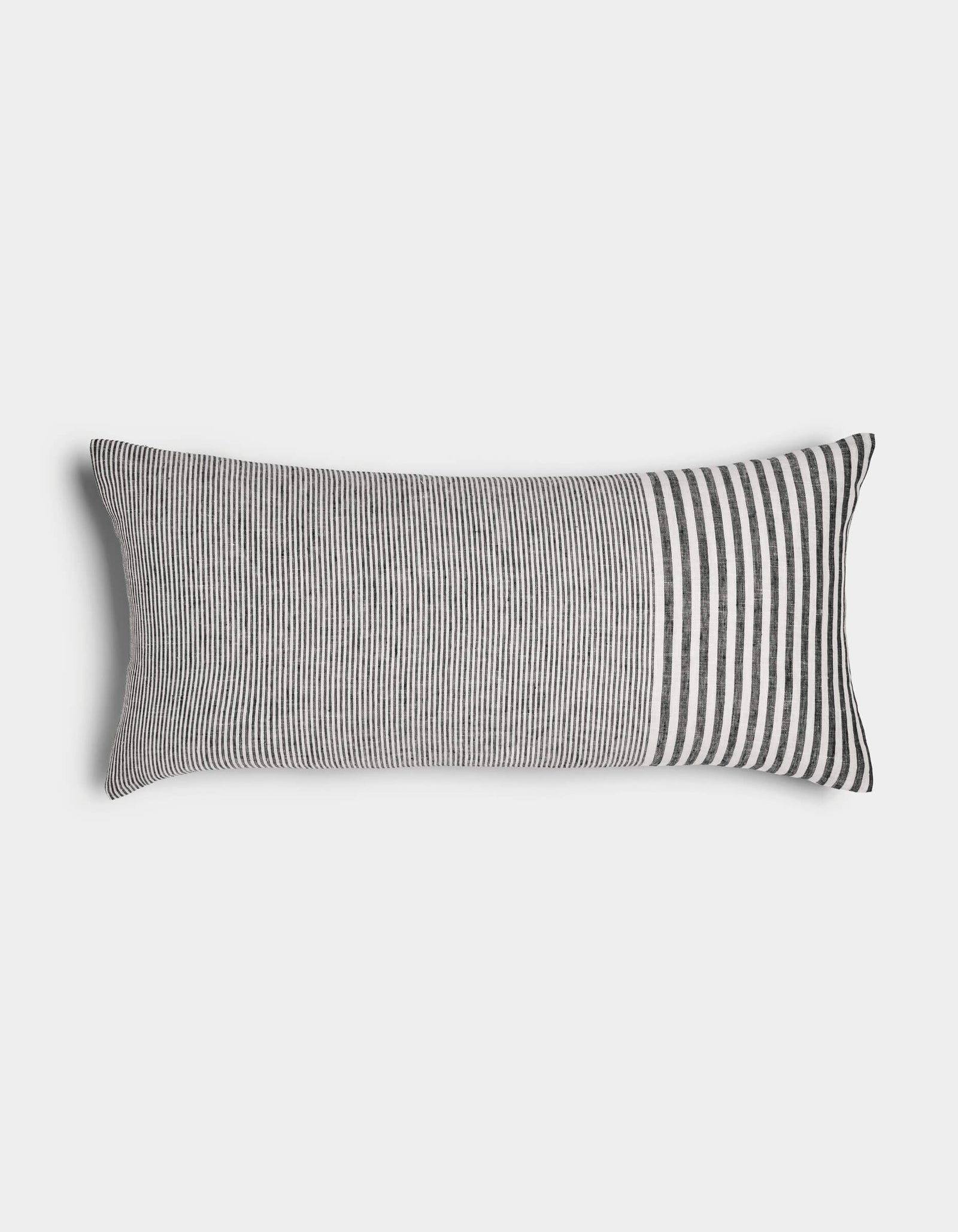 The Cozy Earth Striped Throw Pillow features thin vertical black and white stripes across most of its rectangular surface, with wider stripes at one end, displayed against a plain white background.