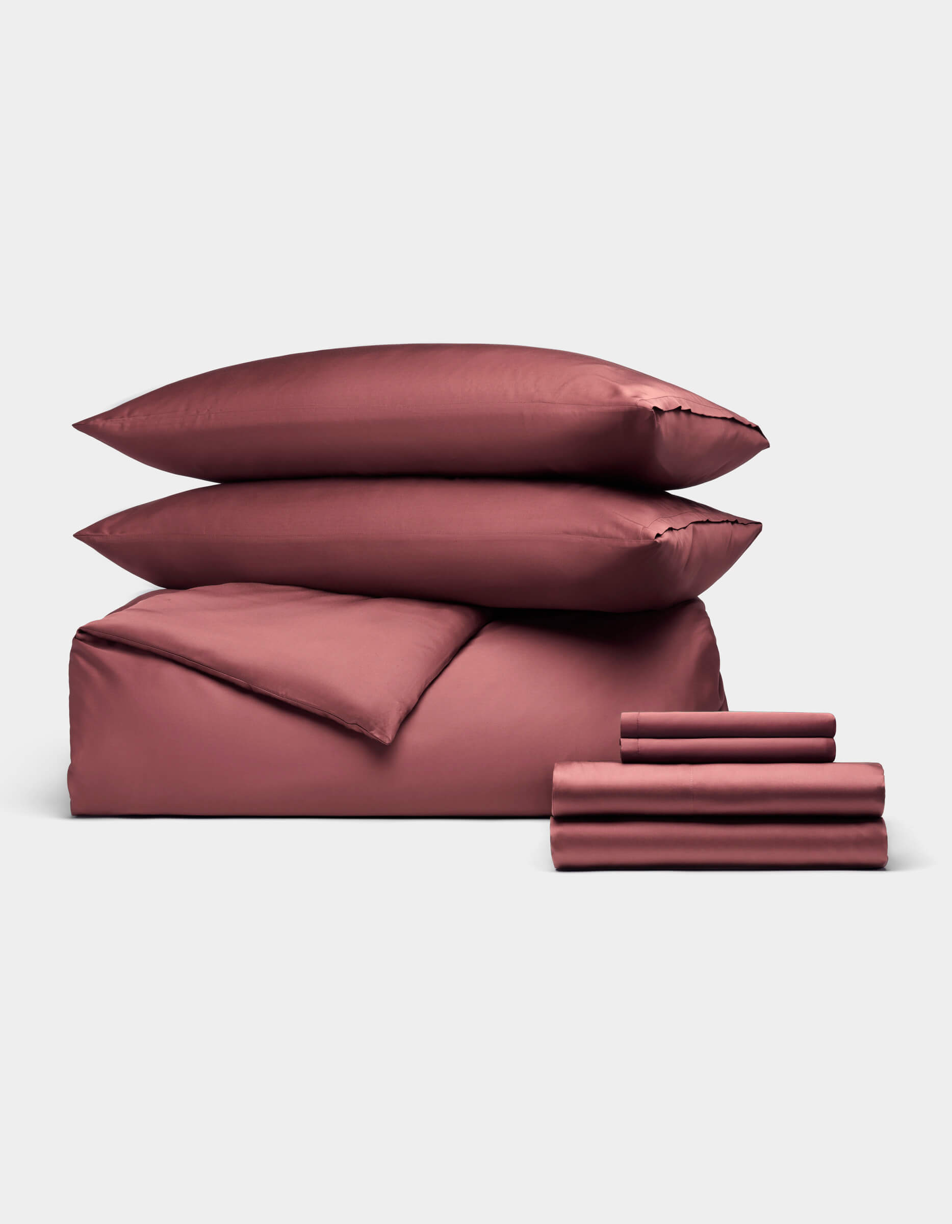 The Cozy Earth Bamboo Bedding Ultimate Bundle features two pillows, a duvet cover, and folded sheets in mauve, all elegantly displayed against a plain light gray background.|Color:Mulberry