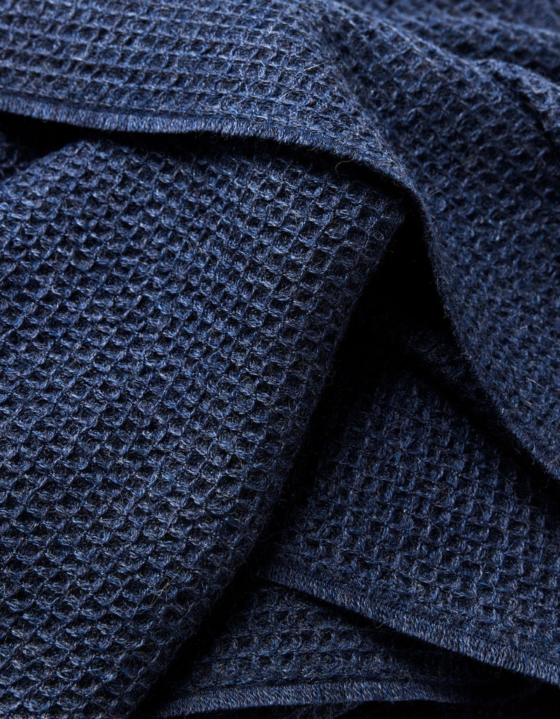 Close-up of the Cozy Earth Alpaca Waffle Throw in dark blue, showing its waffle-textured fabric with overlapping folds that emphasize the raised grid pattern and soft appearance.