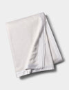 The Cozy Earth Bamboo Blanket, featuring a smooth satin border, is shown folded on a light gray background. |Color:White