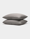 Two neatly stacked Bamboo Coverlet Shams by Cozy Earth in gray with stripes, displayed on a plain white background.|Color:Charcoal
