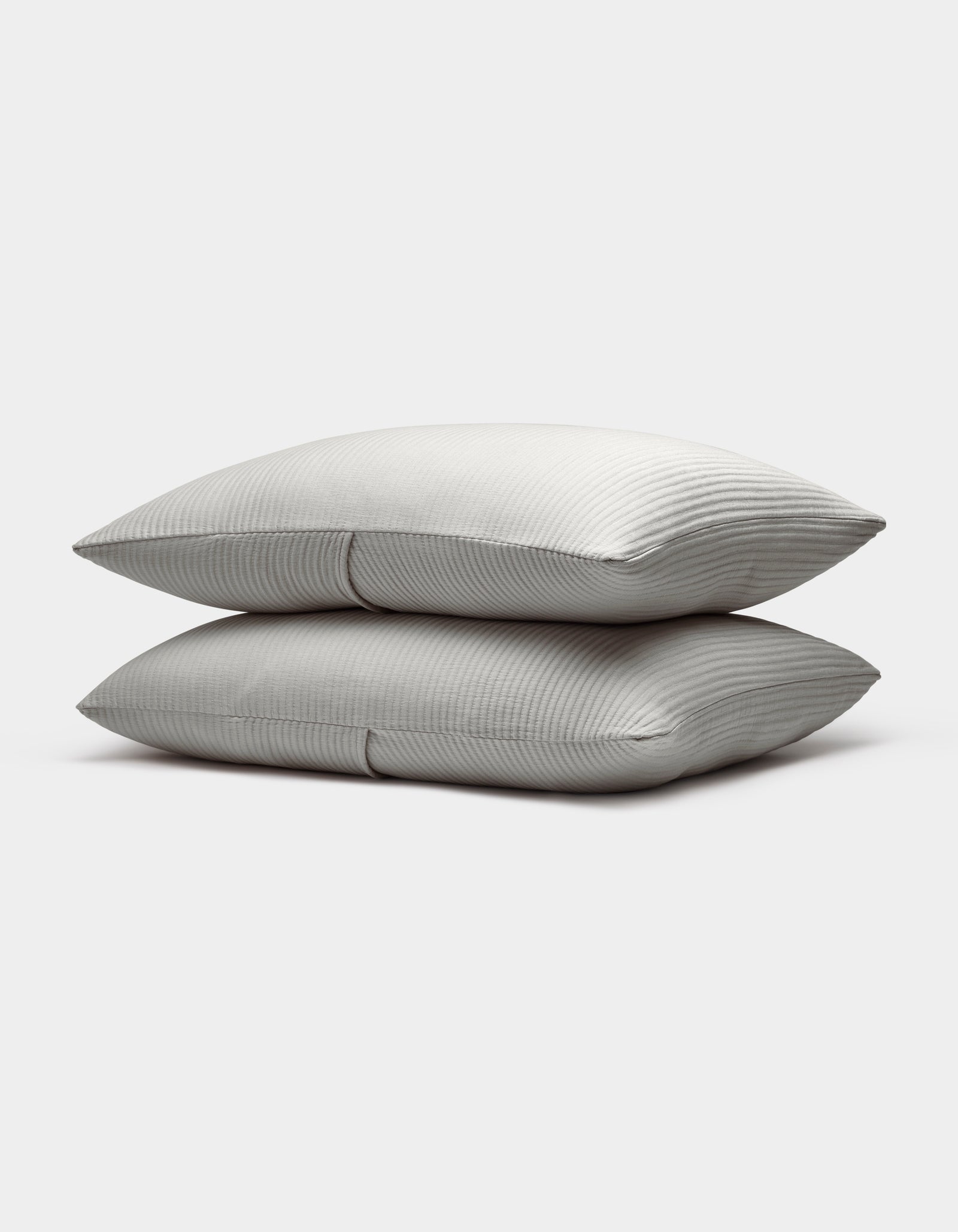 Two neatly stacked Bamboo Coverlet Shams by Cozy Earth, light gray with a subtle striped pattern, are displayed on a plain white background.