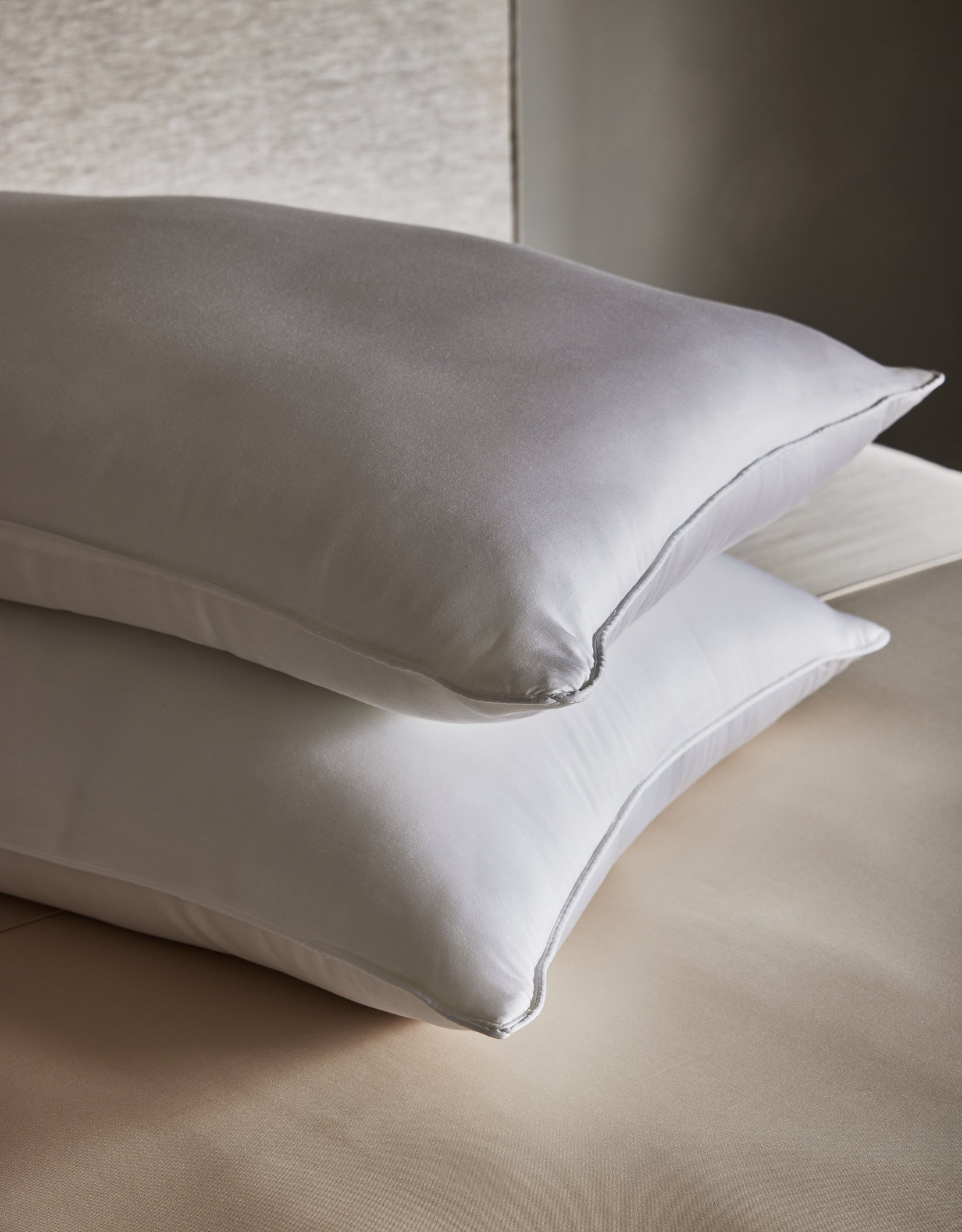 Two Cozy Earth Bamboo Down Alternative Pillows are neatly stacked on a beige bed with smooth, clean sheets, set against a neutral background.Standard King