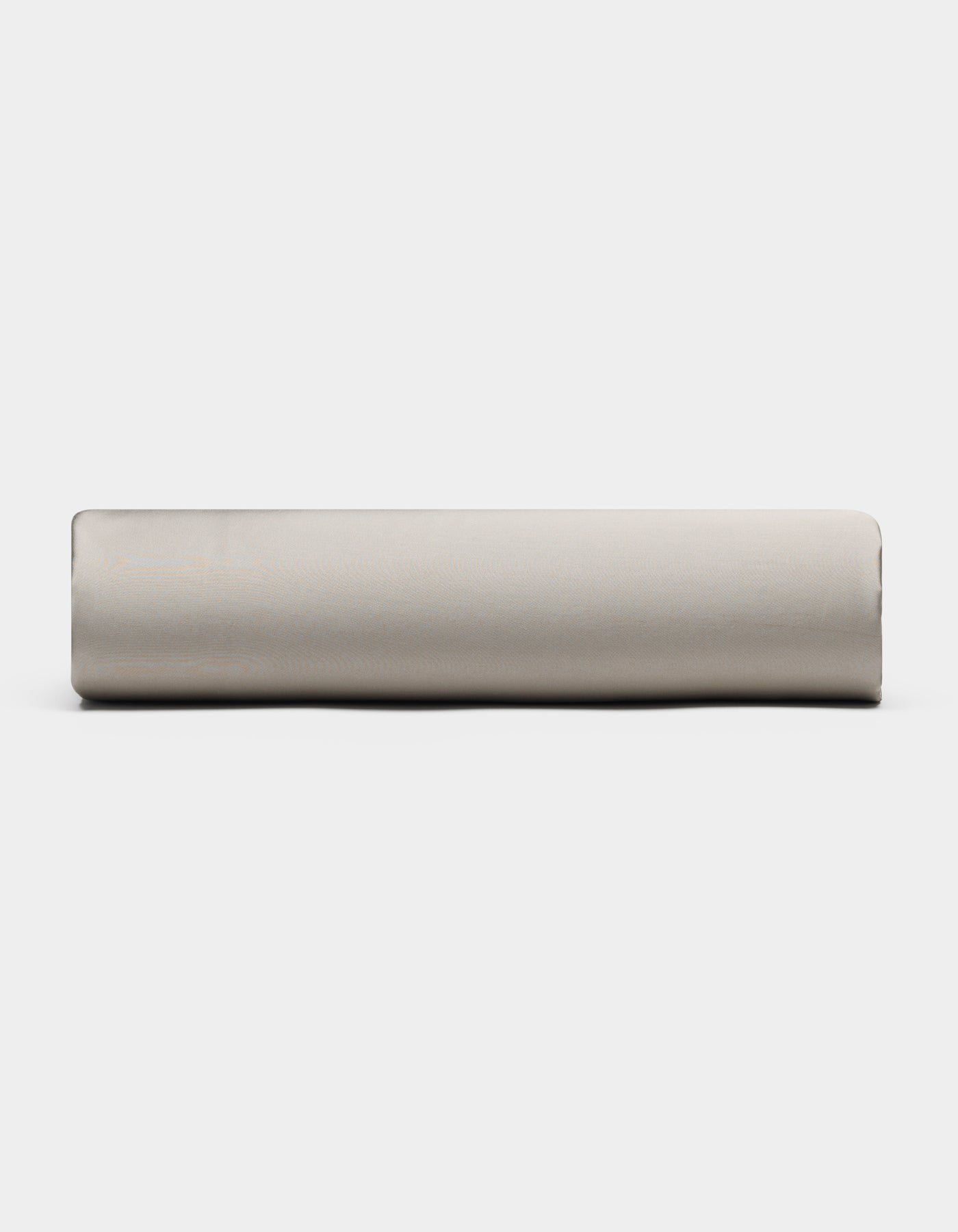 A Bamboo Fitted Sheet by Cozy Earth, in light gray, is rolled up and placed horizontally against a plain white background, viewed from the side.