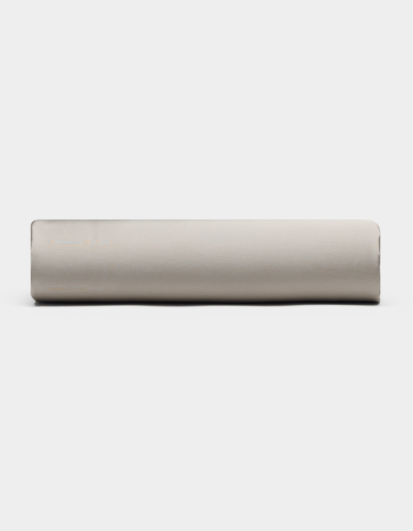 A Bamboo Fitted Sheet by Cozy Earth, in light gray, is rolled up and placed horizontally against a plain white background, viewed from the side.