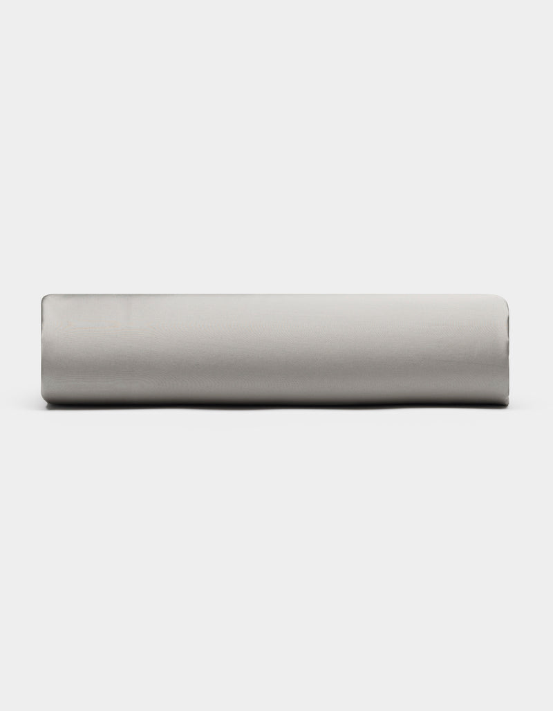 A Bamboo Fitted Sheet by Cozy Earth in light gray is displayed from the side against a plain white background.