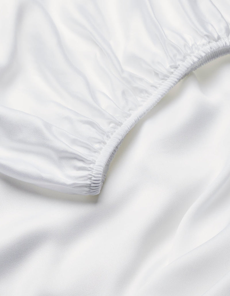 Close-up of Cozy Earth's Bamboo Fitted Sheet, featuring smooth white fabric with elastic edging and soft folds, highlighting its clean, silky texture.
