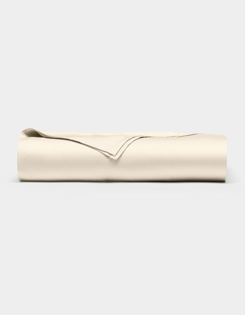 The Cozy Earth Bamboo Flat Sheet, in a light beige color, is neatly folded and displayed against a plain, light gray background.
