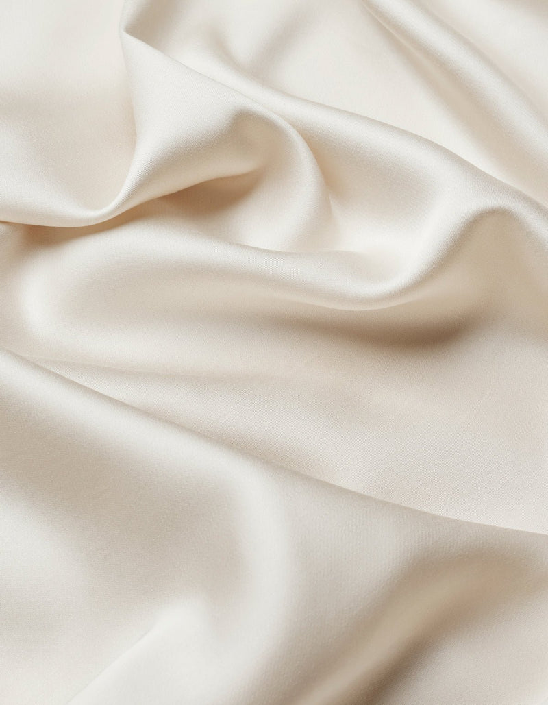 Close-up of the Cozy Earth Bamboo Flat Sheet reveals smooth, ivory fabric with soft folds and a subtle sheen, creating a flowing and elegant texture.