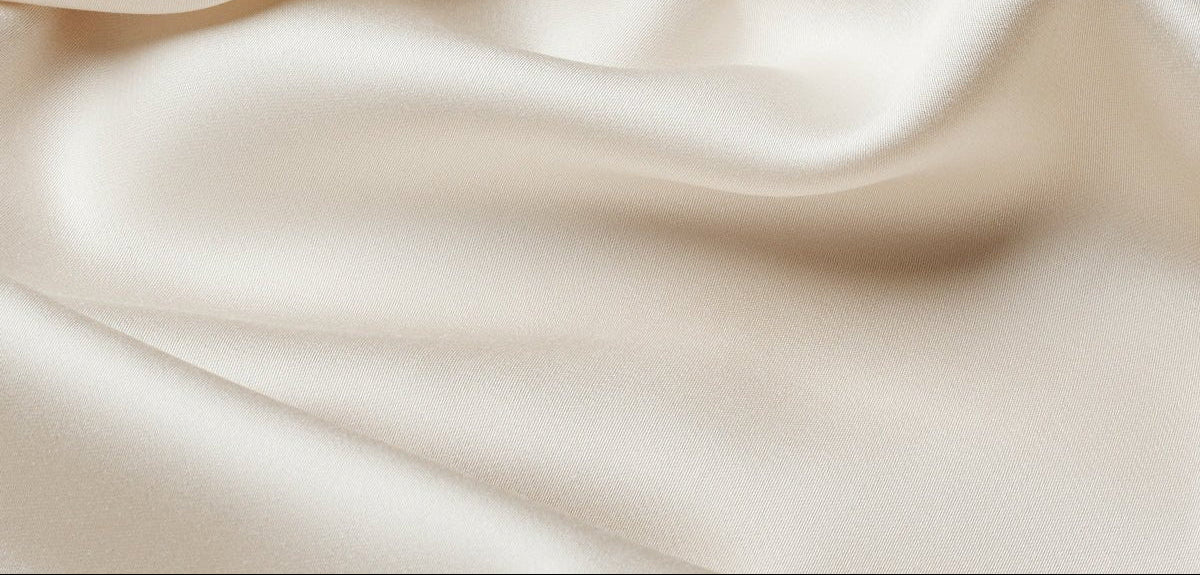 Close-up of Cozy Earth Bamboo Sheet Set in smooth, ivory satin with soft folds and gentle waves, showcasing its silky texture and subtle sheen.