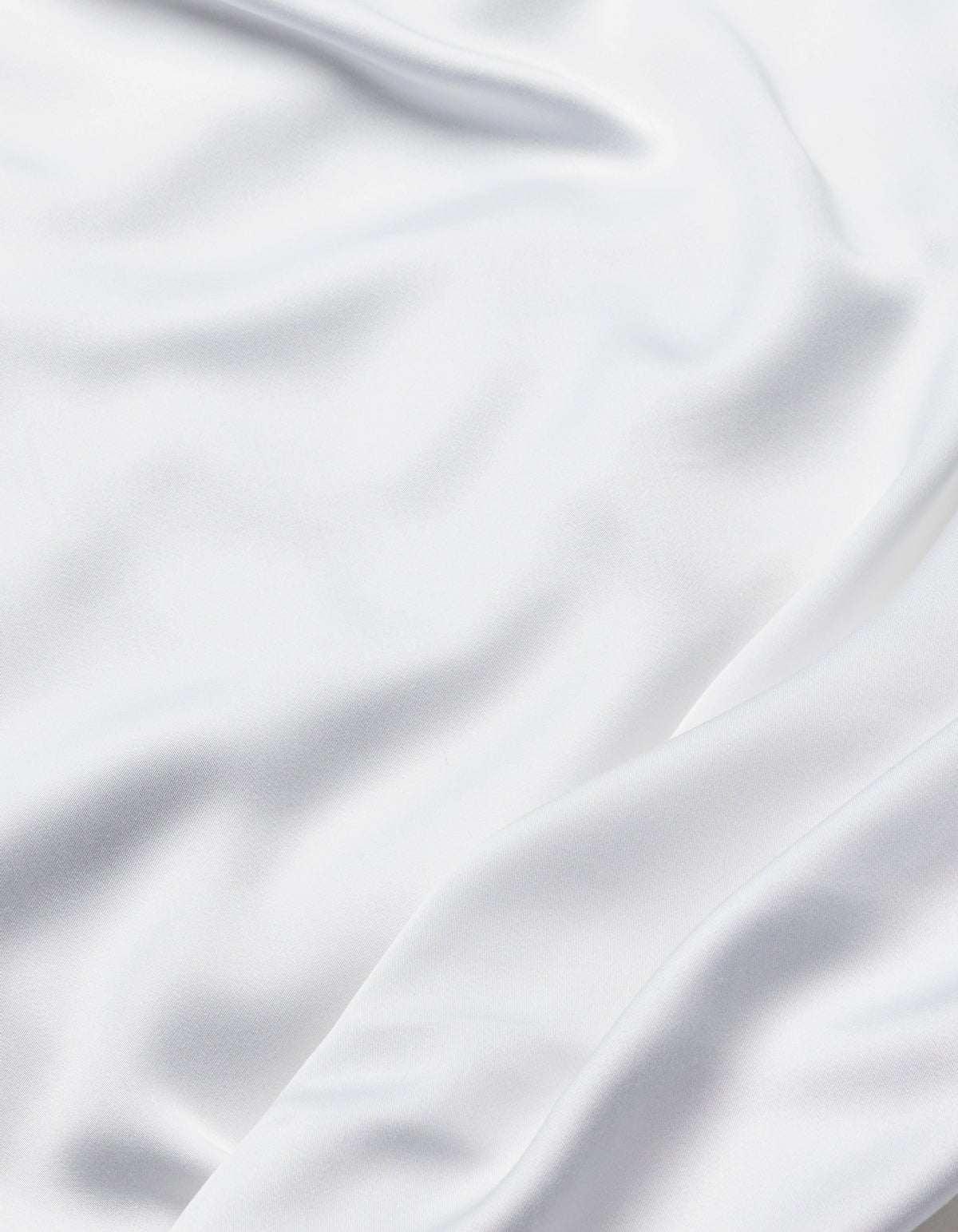 The Cozy Earth Bamboo Sheet Set features smooth white fabric with soft folds and flowing creases, offering a silky, elegant texture.