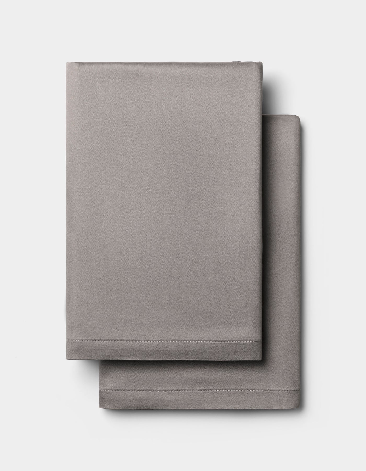 Two light gray Cozy Earth Bamboo Pillowcases, neatly folded and stacked against a plain white background.
