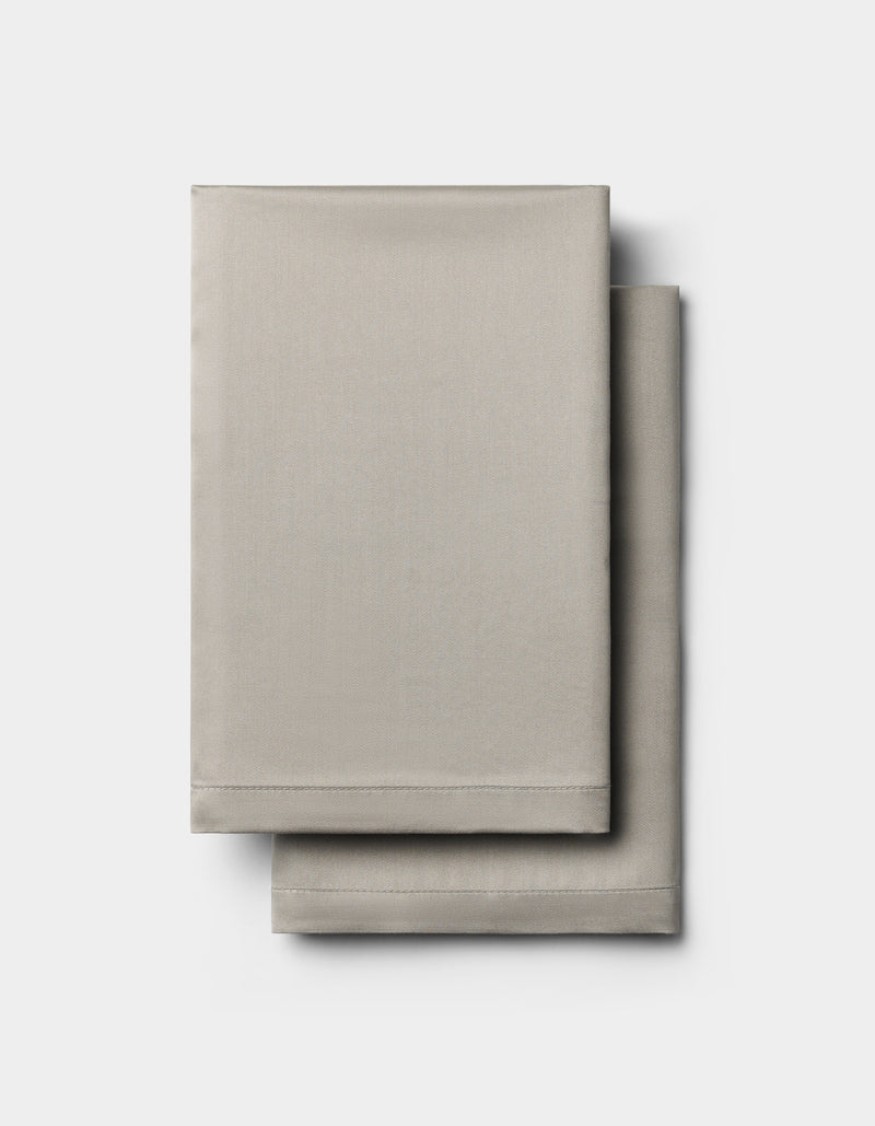 Two neatly folded Cozy Earth Bamboo Pillowcases in light gray are stacked on top of each other against a plain white background.