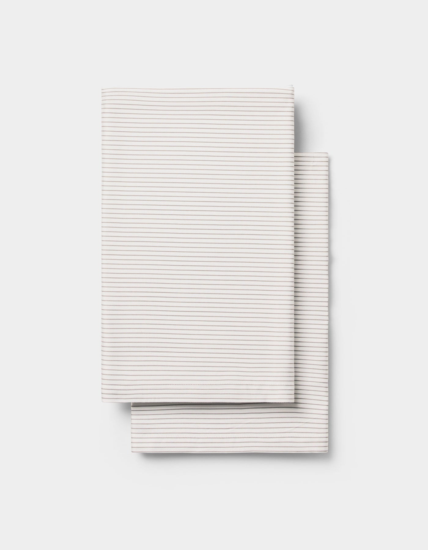 Two neatly folded, light-colored Cozy Earth Bamboo Pillowcases with thin, subtle horizontal stripes, placed one over the other on a plain white background.
