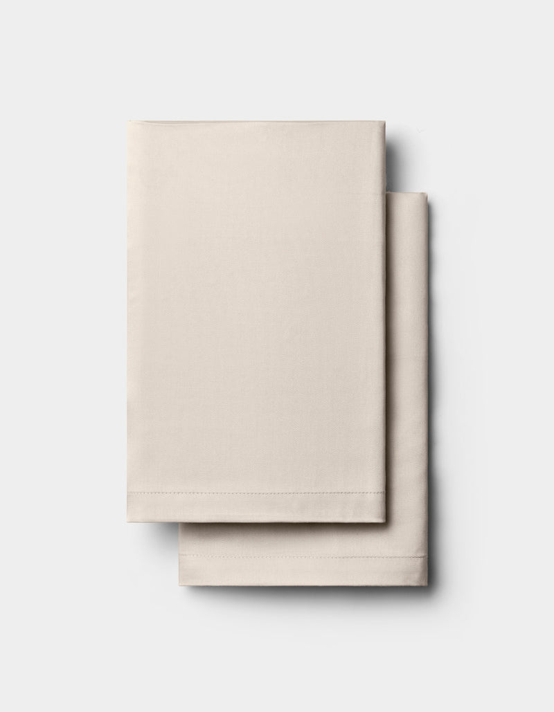 Two neatly folded, light beige Cozy Earth Bamboo Pillowcases are stacked on a plain white background.