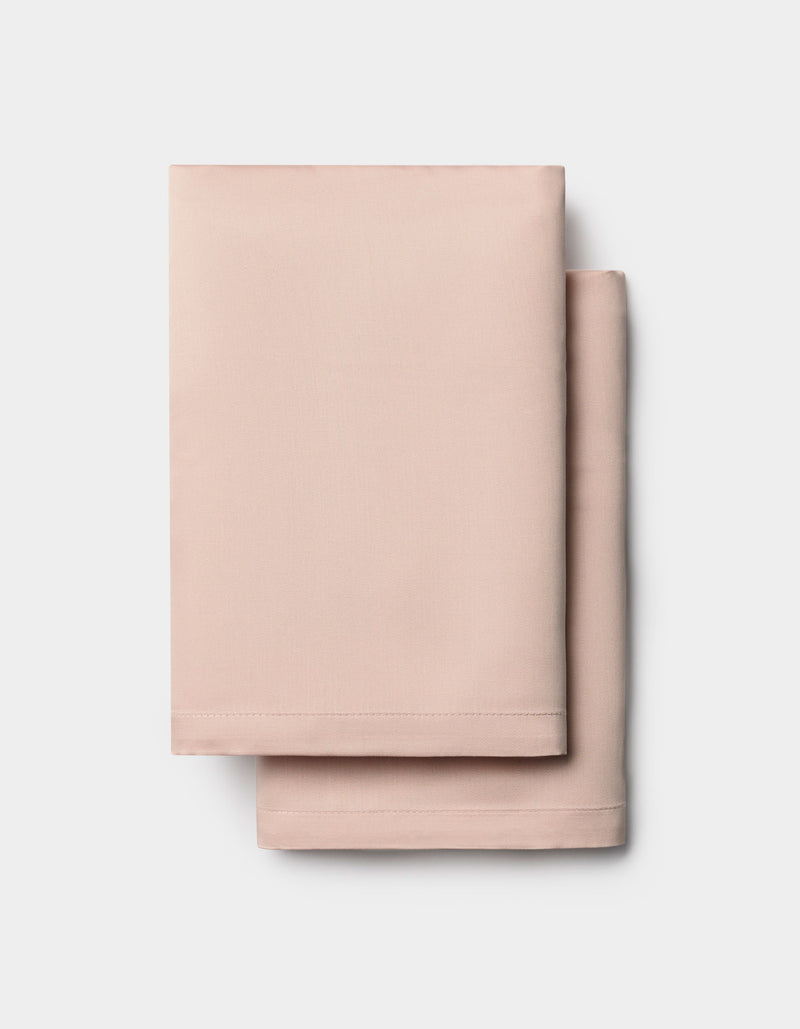 Two neatly folded light pink Cozy Earth Bamboo Pillowcases stacked on a white background.