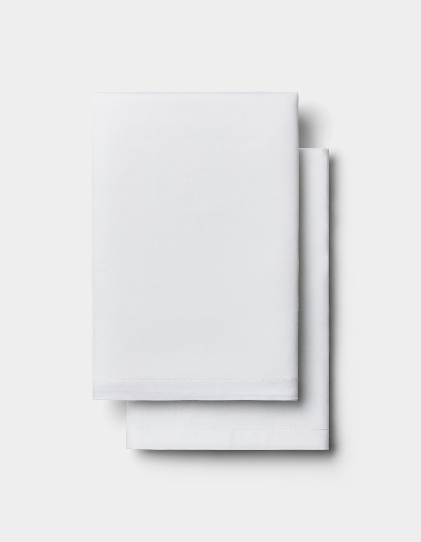 Two neatly folded Cozy Earth Bamboo Pillowcases stacked on top of each other against a plain light background.|Color:White