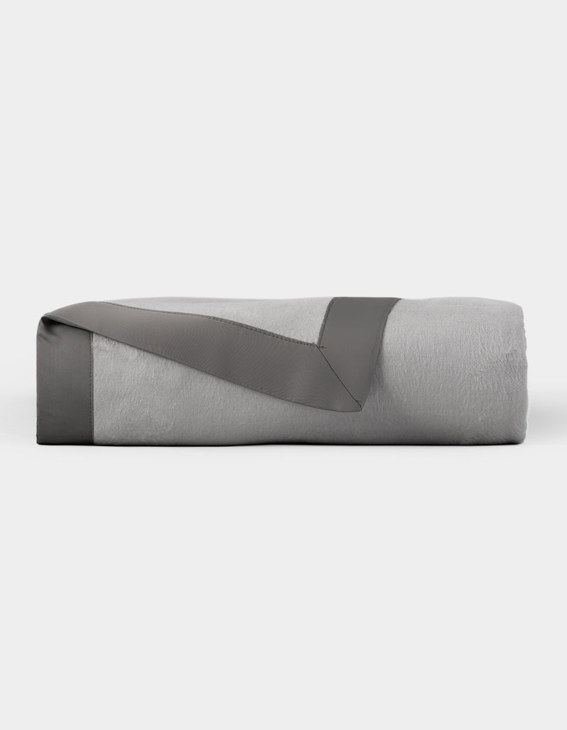 The Cozy Earth Bamboo Blanket is neatly folded, featuring a light gray color with a dark gray satin trim, and displayed on a plain white background.