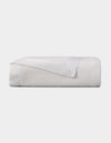 The Cozy Earth Bamboo Blanket, featuring a satin trim, is neatly folded and displayed against a plain light background. |Color:White