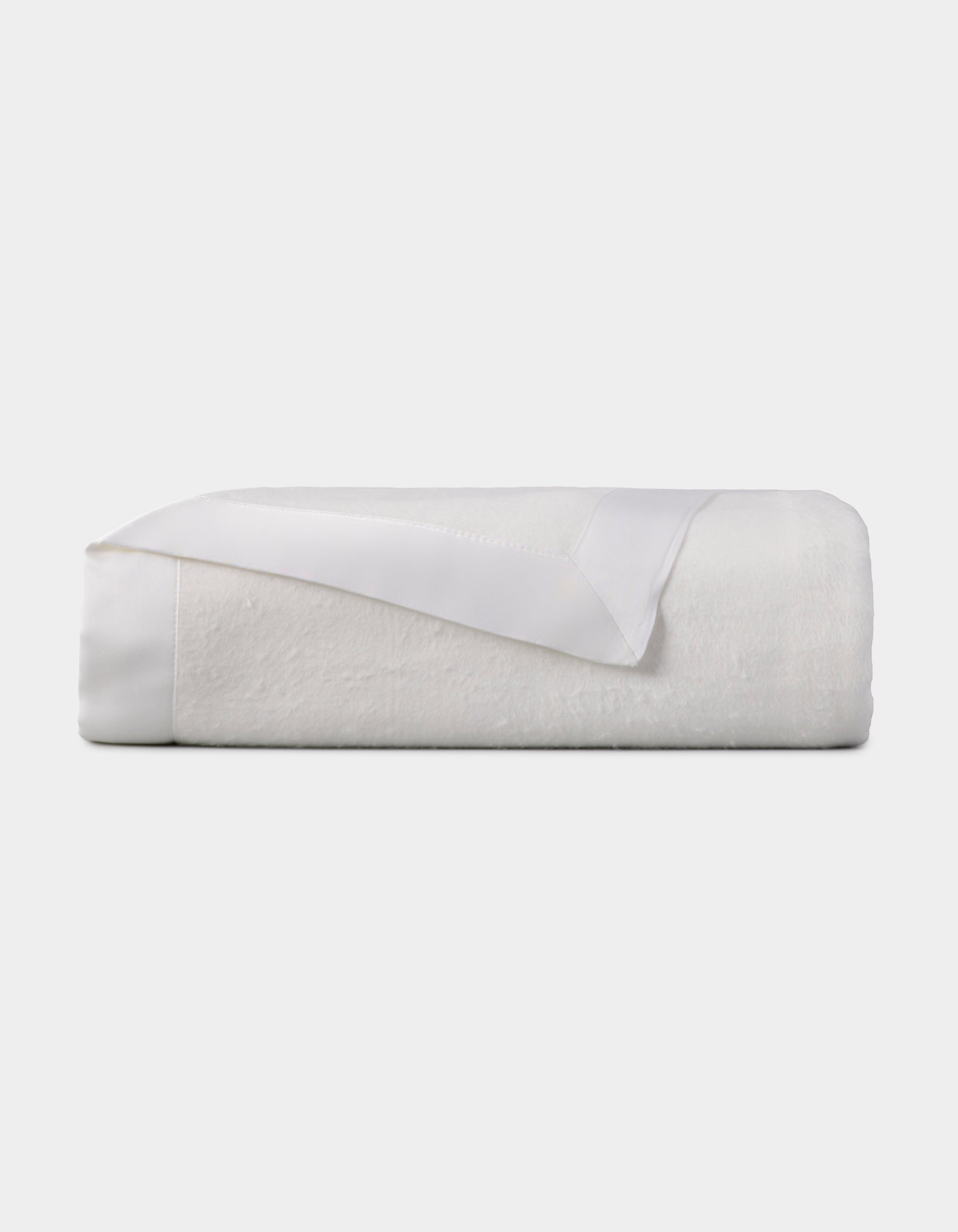 The Cozy Earth Bamboo Blanket, featuring a satin trim, is neatly folded and displayed against a plain light background. 