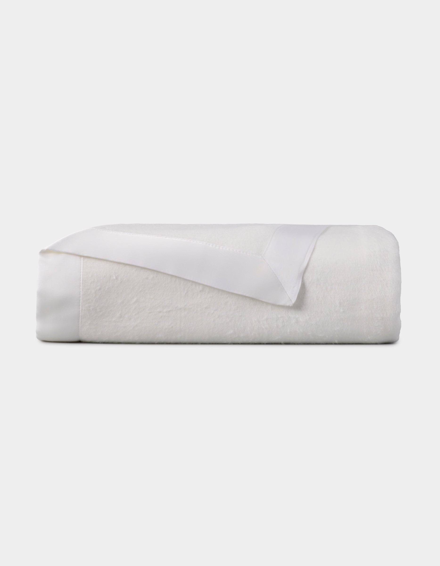 The Cozy Earth Bamboo Blanket, featuring a satin trim, is neatly folded and displayed against a plain light background. |Color:White