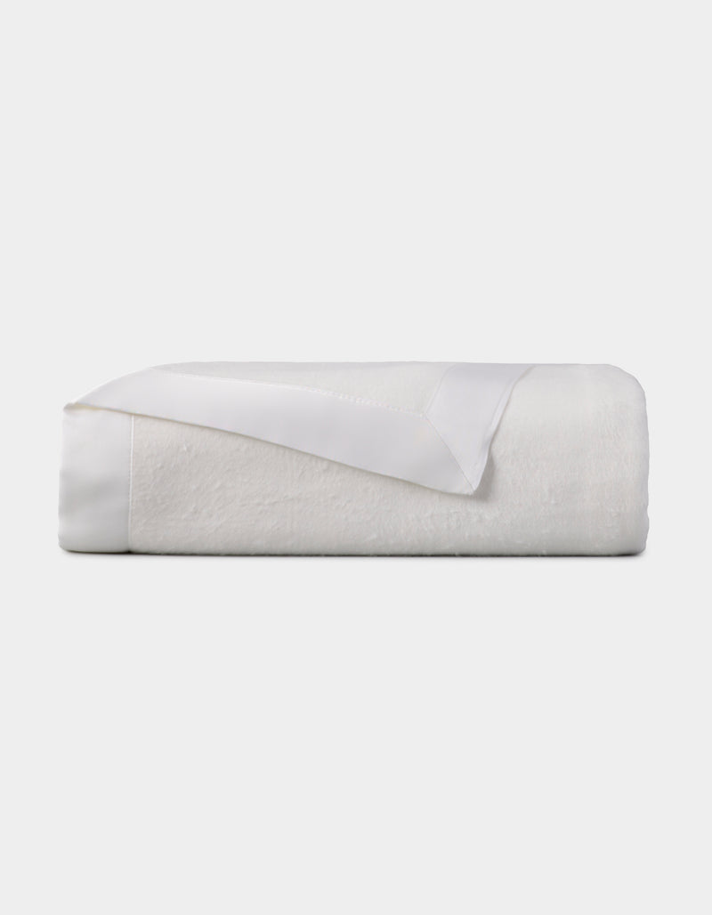 The Cozy Earth Bamboo Blanket, featuring a satin trim, is neatly folded and displayed against a plain light background.