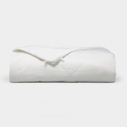 The Bamboo Viscose All Season Comforter by Cozy Earth, featuring a neatly folded white design with a subtle sheen, is displayed against a plain light background.
