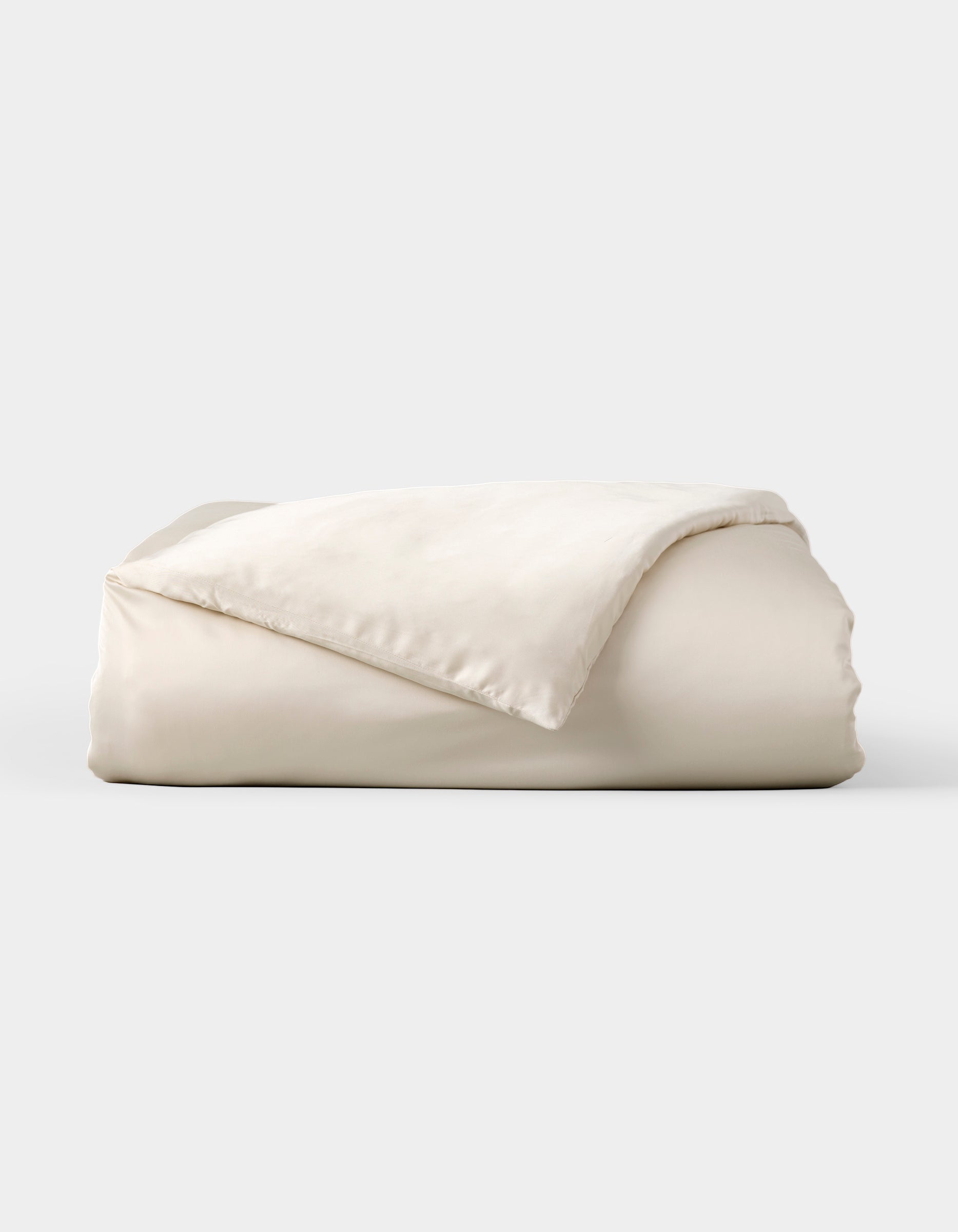 The Cozy Earth Bamboo Duvet Cover, shown neatly folded with one corner flipped to reveal its soft, smooth fabric, is displayed against a plain light gray background.|Color:Oat