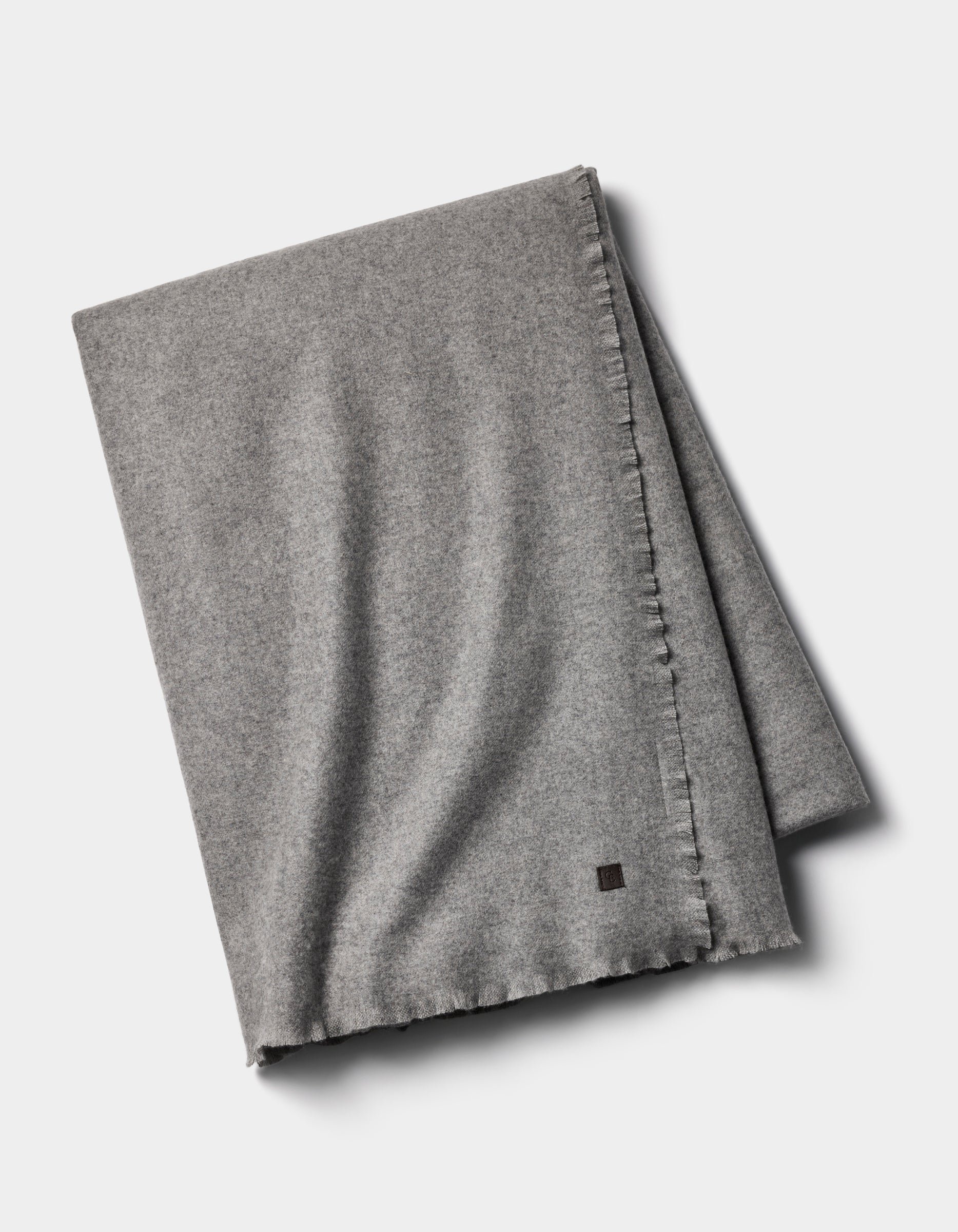 The Cozy Earth Cashmere Fringe Blanket, in light gray, features subtle edge stitching and elegant fringe, neatly folded and displayed on a white background.|Color:Pebble