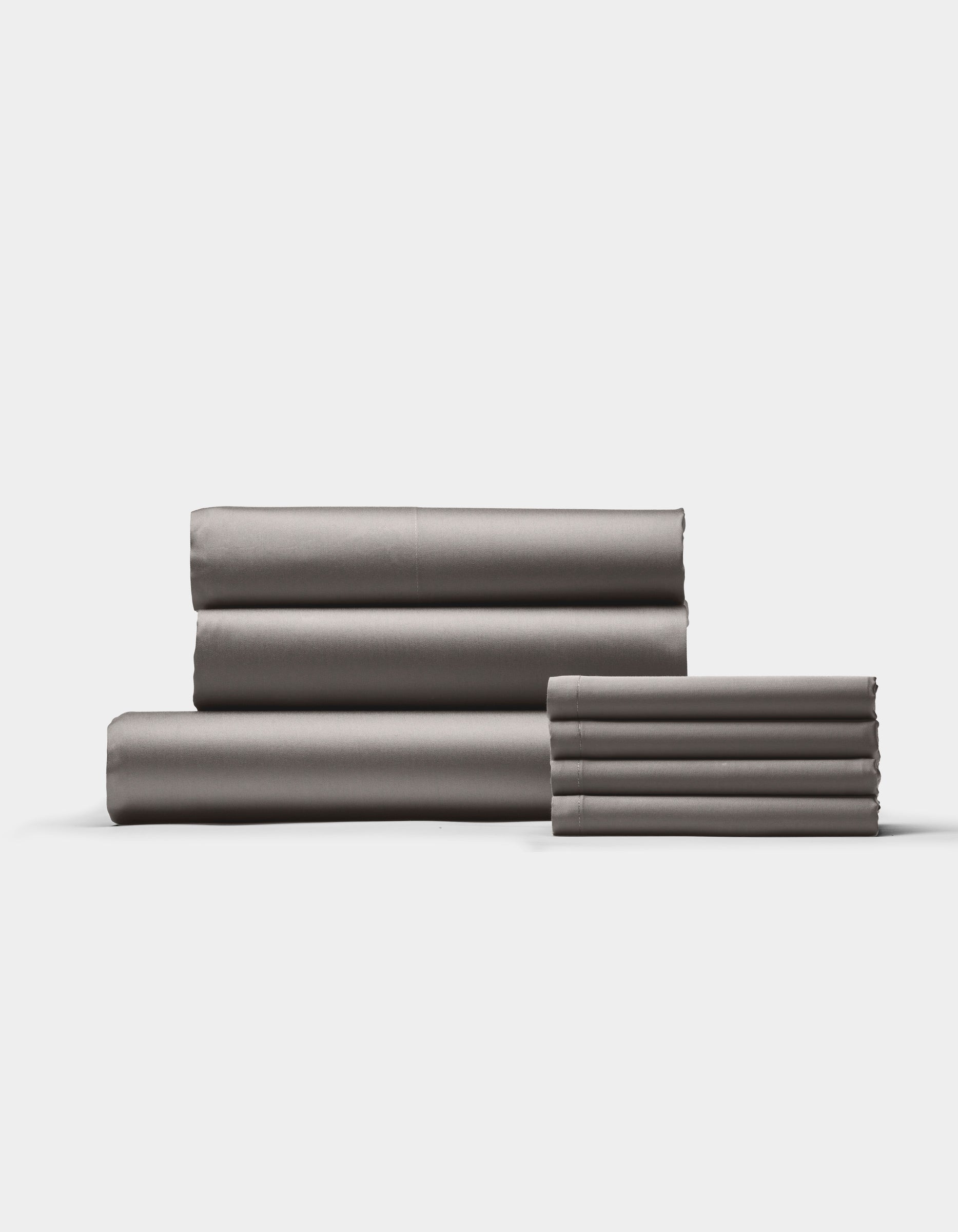 The Cozy Earth Bamboo Bedding Core Bundle features neatly folded gray bed sheets arranged in two stacks against a plain white background.|Color:Charcoal