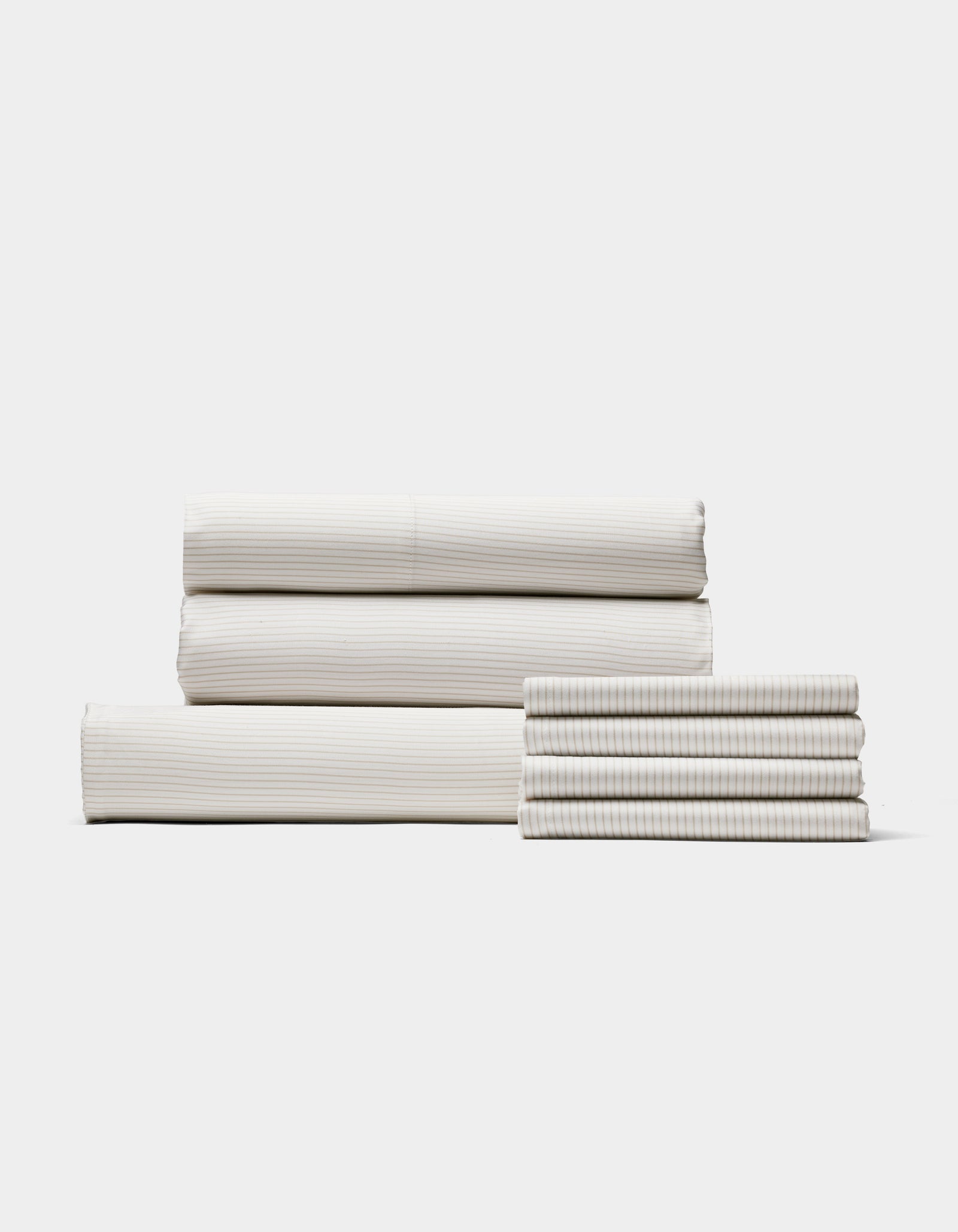 Four neatly folded sets of Cozy Earth Bamboo Bedding Core Bundle sheets are stacked in two piles against a plain white background, featuring subtle, light-colored vertical stripes.