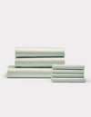 Cozy Earth's Bamboo Bedding Core Bundle, featuring neatly folded light green bed sheets and pillowcases, is stacked in two groups against a plain white background.|Color:Laurel