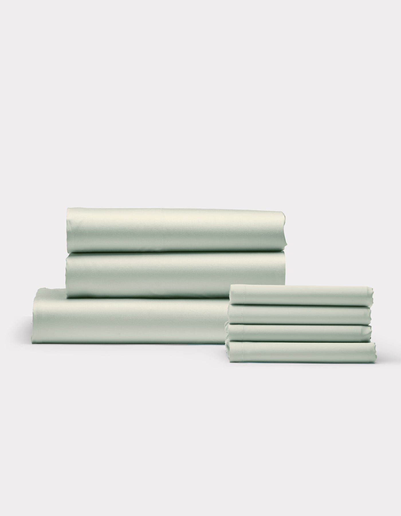 Cozy Earth's Bamboo Bedding Core Bundle, featuring neatly folded light green bed sheets and pillowcases, is stacked in two groups against a plain white background.|Color:Laurel