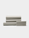 The Cozy Earth Bamboo Bedding Core Bundle, featuring neatly folded light gray sheets and pillowcases, is stacked on a white background with three larger sheets on the left and pillowcases on the right.|Color:Light Grey