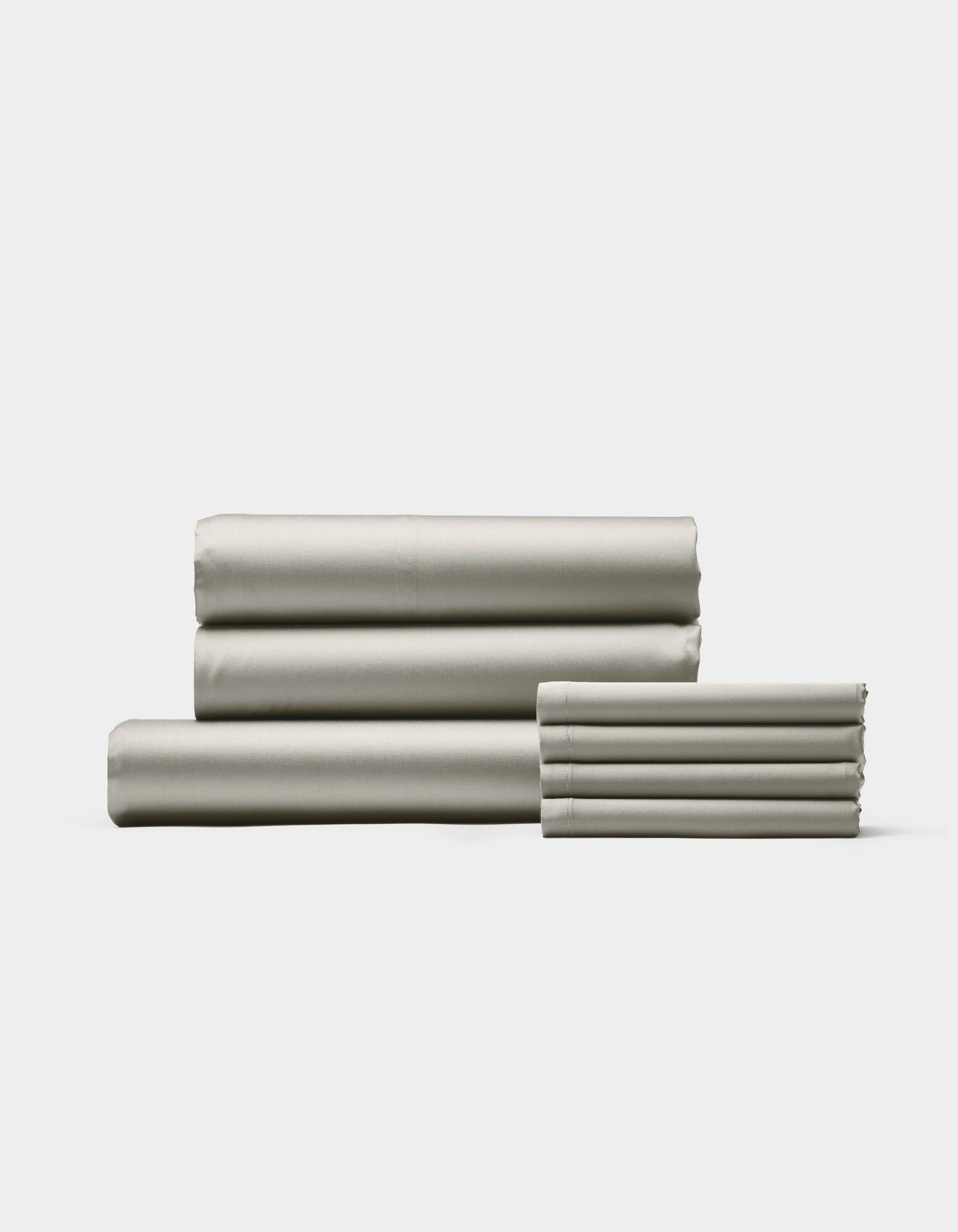 The Cozy Earth Bamboo Bedding Core Bundle, featuring neatly folded light gray sheets and pillowcases, is stacked on a white background with three larger sheets on the left and pillowcases on the right.
