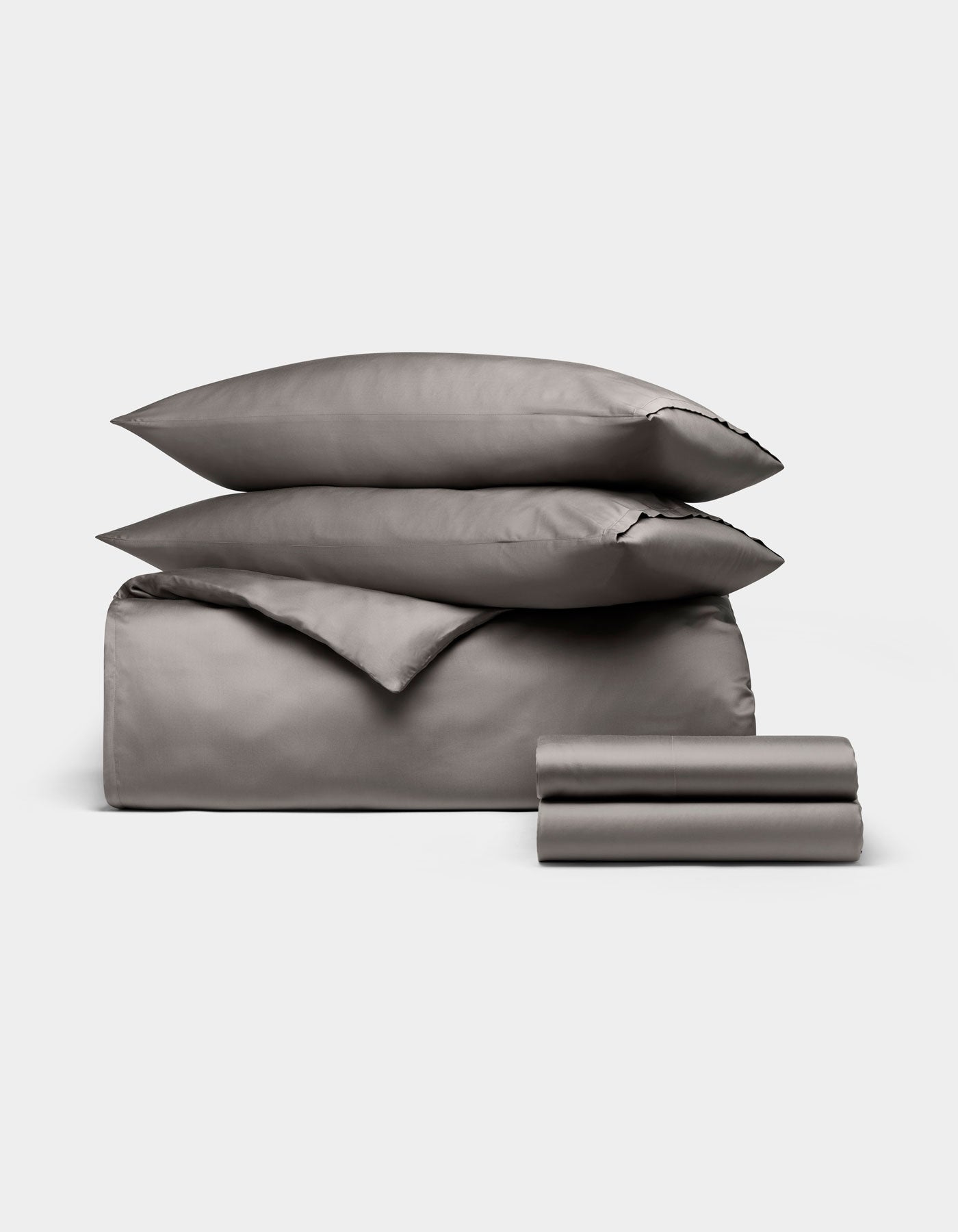 The Cozy Earth Bamboo Bedding Deluxe Bundle features neatly folded gray sheets, pillowcases, a duvet cover, flat and fitted sheets, and two stacked pillows displayed on a plain white background.|Color:Charcoal