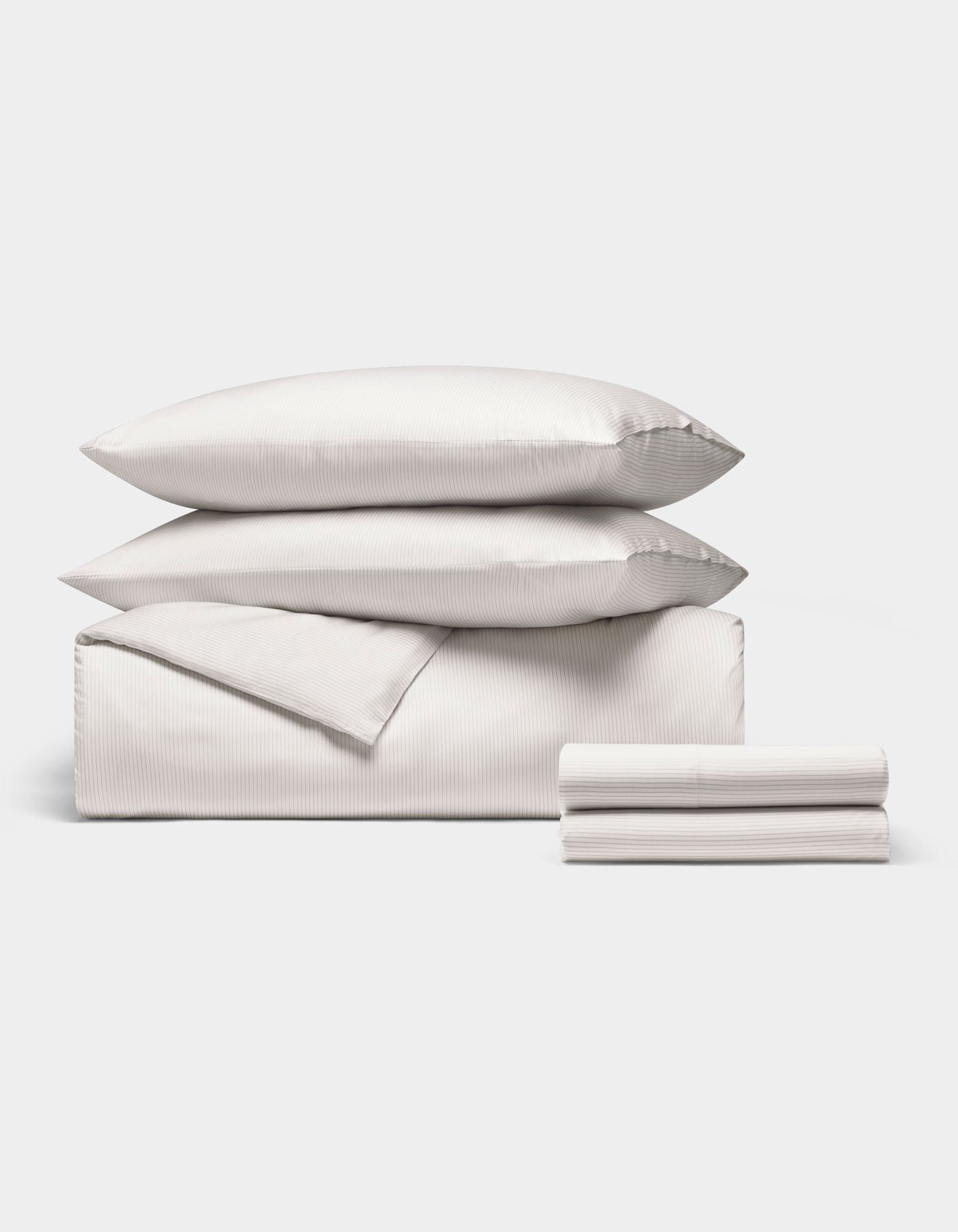 The Cozy Earth Bamboo Bedding Deluxe Bundle features two stacked pillows, a folded duvet, and folded sheets, all in white, neatly displayed on a plain white background.