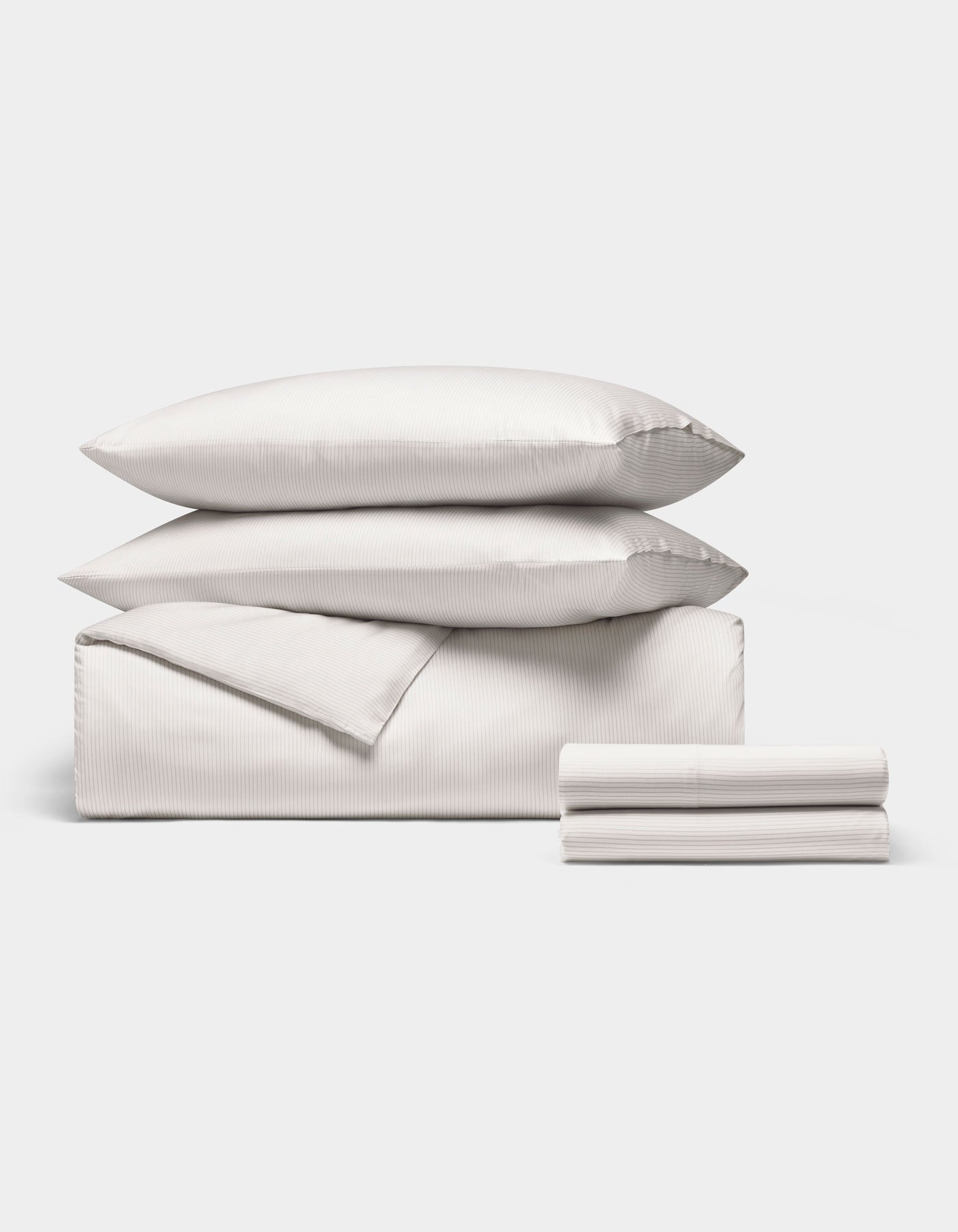 The Cozy Earth Bamboo Bedding Deluxe Bundle features two stacked pillows, a folded duvet, and folded sheets, all in white, neatly displayed on a plain white background.