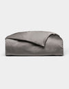 A neatly folded, shiny gray Bamboo Duvet Cover by Cozy Earth is displayed on a plain white background.|Color:Charcoal