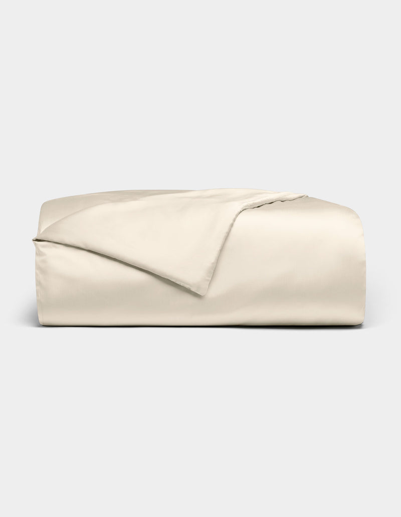 The Cozy Earth Bamboo Duvet Cover is shown neatly folded in light beige, with one corner turned back, set against a plain light gray background.