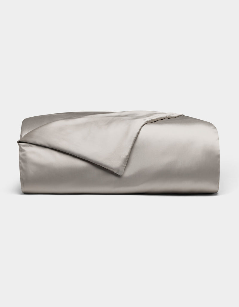 The Cozy Earth Bamboo Duvet Cover, shown neatly folded in light gray with a smooth, shiny satin finish, is displayed on a plain white background.