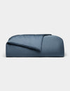 The Cozy Earth Bamboo Duvet Cover, in dark blue and rectangular shape, features plush fabric with a partially folded comforter, displayed against a plain light gray background.|Color:Pacific Blue