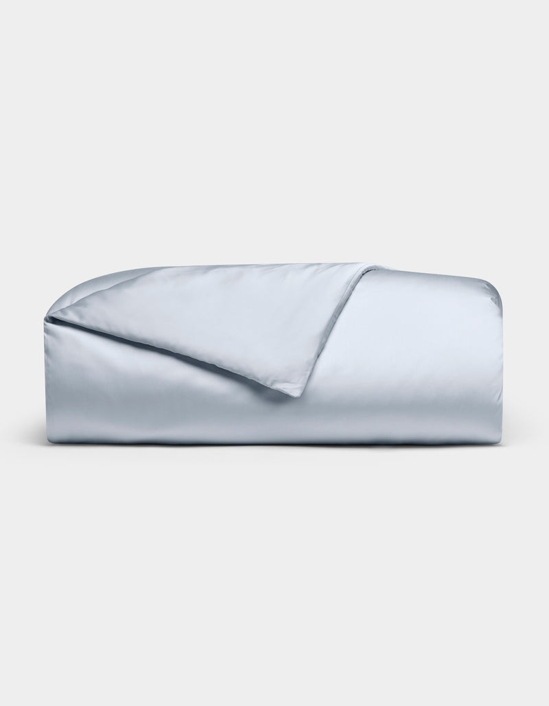 The Cozy Earth Bamboo Duvet Cover in light blue is neatly folded against a white background, with one corner flipped to reveal its smooth, silky texture.