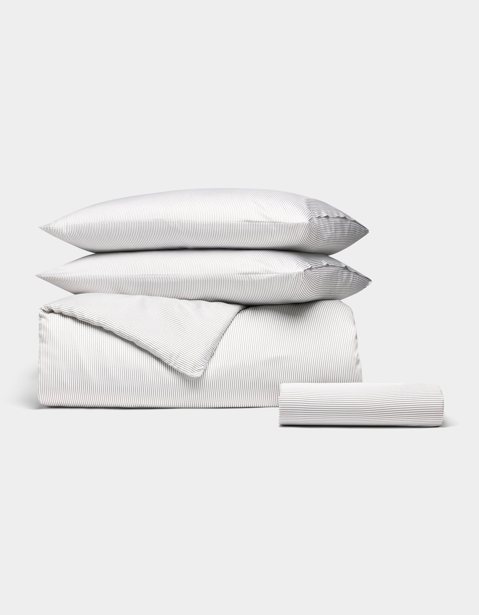 The Bamboo Bedding Essential Bundle by Cozy Earth features a white set with thin gray pinstripes—two pillows, a duvet cover, and a fitted sheet—neatly folded and displayed against a plain white background. 