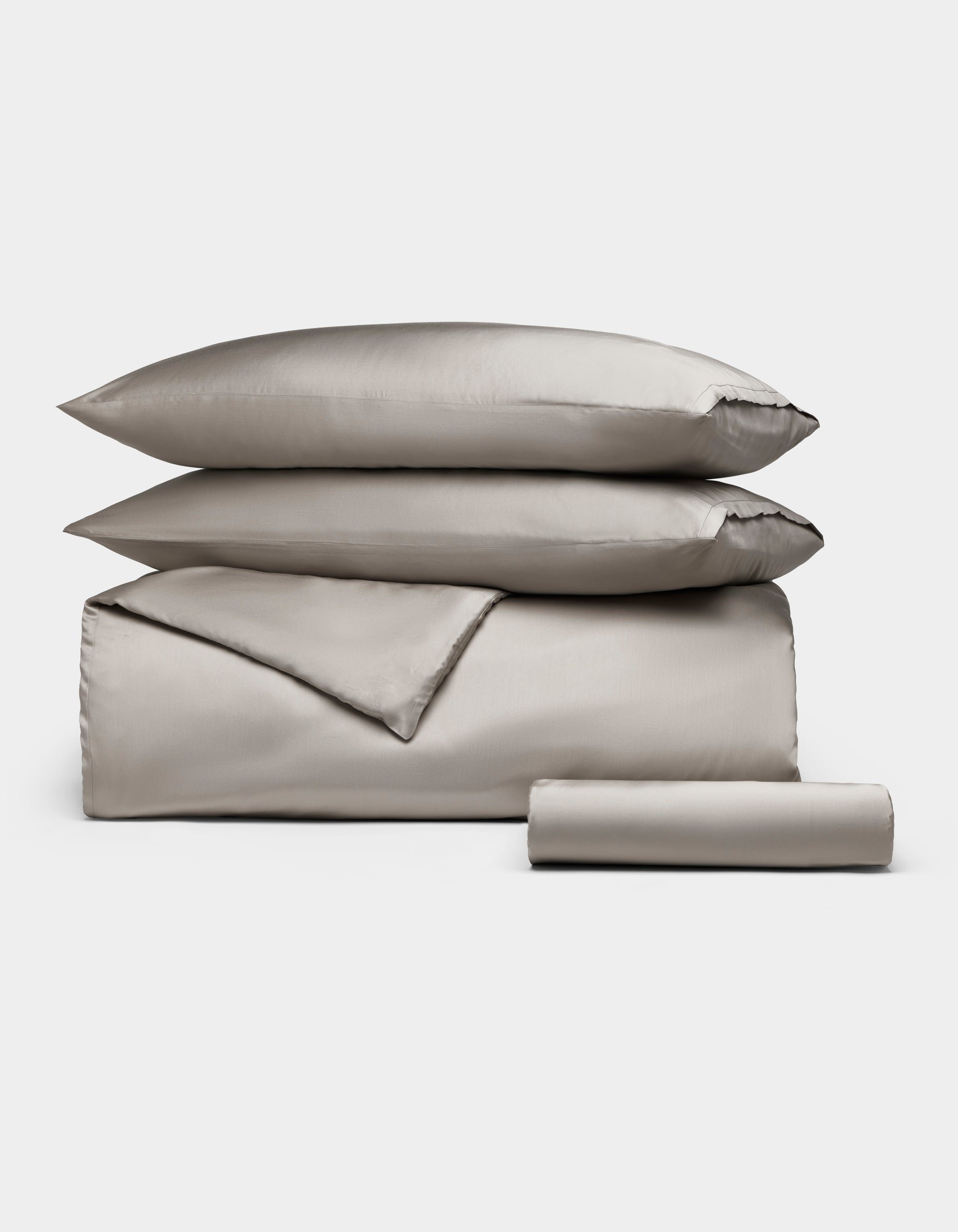 The Cozy Earth Bamboo Bedding Essential Bundle features neatly folded light gray bedding—a comforter, two stacked pillows, and a rolled sheet—displayed on a plain white background.