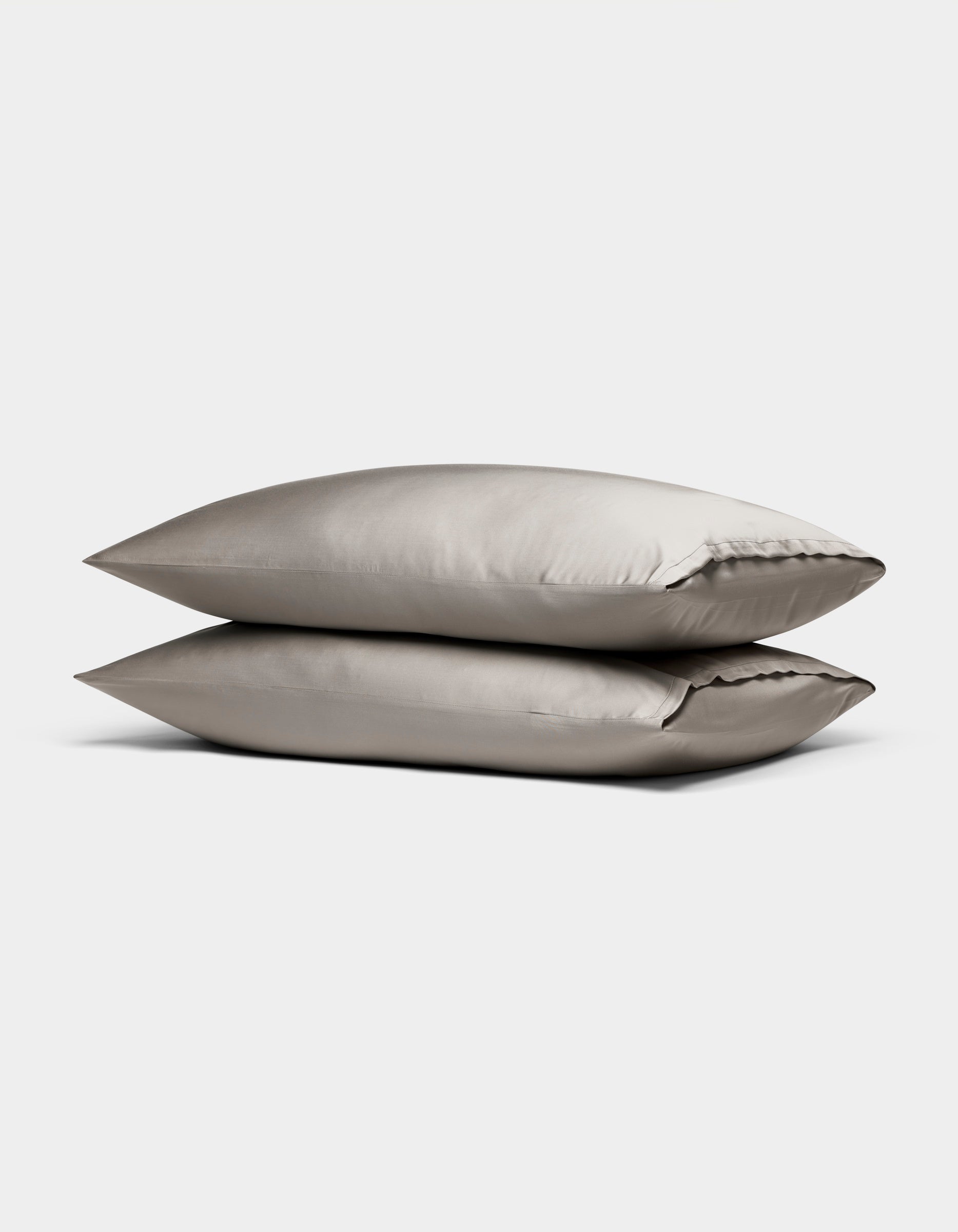 Two Cozy Earth Bamboo Pillowcases in light gray satin are stacked against a plain white background.|Color:Dove Grey