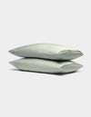 Two Cozy Earth Bamboo Pillowcases in light green are stacked neatly on top of each other against a plain, light gray background.|Color:Laurel