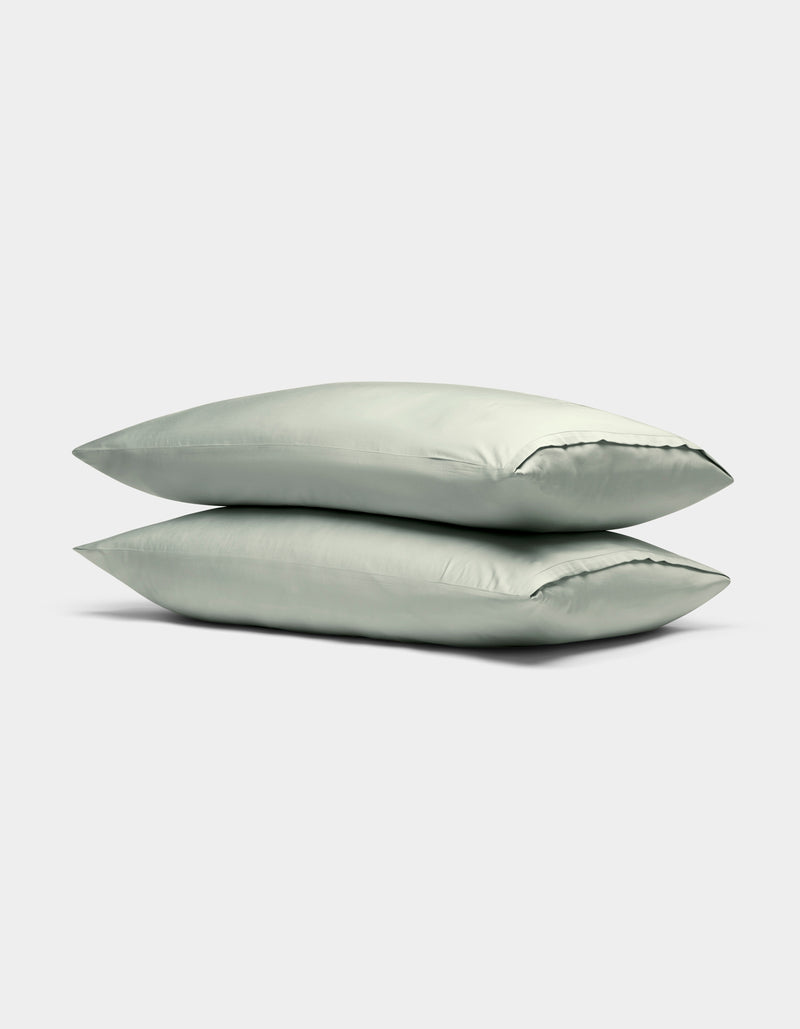 Two Cozy Earth Bamboo Pillowcases in light green are stacked neatly on top of each other against a plain, light gray background.