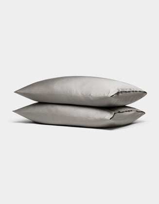 Two Cozy Earth Bamboo Pillowcases in light gray are stacked neatly on top of each other against a plain white background.|Color:Light Grey